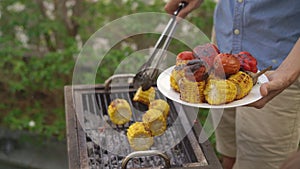 A young man cooks vegetables and shrimps on a barbeque in his backyard