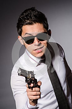 Young man in cool sunglasses holding gun isolated