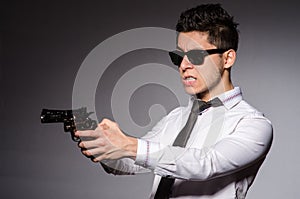 Young man in cool sunglasses holding gun isolated