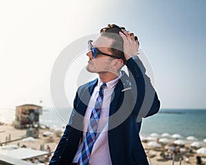 Young man corrects his hair on the background of the sea and sky