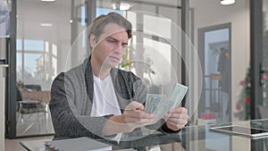 Young Man Counting Money in Office