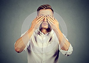 Young man covering eyes with both hands