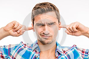 Young man covering his ears ignoring noise