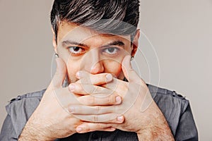 Young man covering mouth with hands. Emotional concept. Diet concept