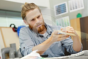 young man craftsman checking wooden surface