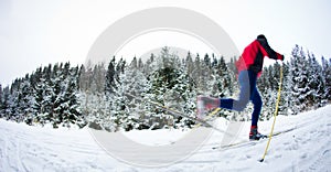 Young man cross-country skiing on a snowy forest trail