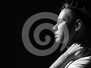 Young man in crown of thorns, martyr with closed eys and arm on his neck side shot