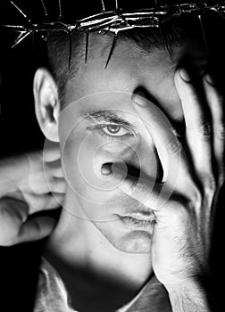 Young man in crown of thorns, martyr covers his face with hand