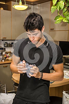 Young Man Crushing Plastic Water Bottle in Kitchen