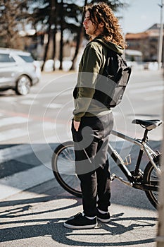 Young man with curly hair enjoying a sunny day outdoors with his bicycle