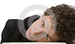 The young man with curly hair has bent to a table