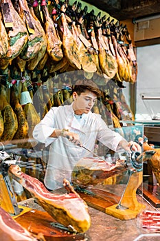 Young man cutting ham in jamoneria