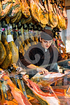 Young man cutting ham in jamoneria