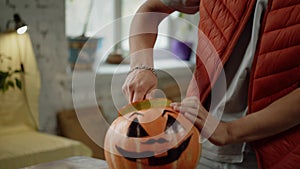 A young man is cutting the top of the halloween pumpkin