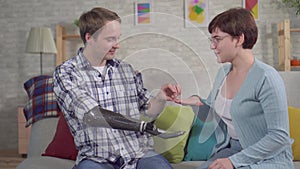 Young man with a cyber prosthetic hand holds an engagement ring and proposes to his girlfriend