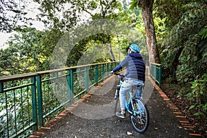 Joven hombre montando una bici en Bosque acera en frío el clima durante el fin de semana 