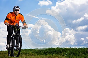 Young man cycling on a rural road through green meadow