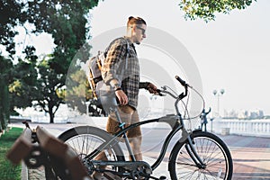 Young man cyclist walks with bicycles on embankment in summer Daily Lifestyle Urban Resting Concept