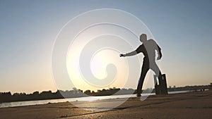 Young man dances actively on a river bank in summer in slo-mo