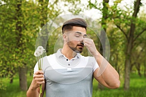 Young man with dandelions suffering from seasonal allergy
