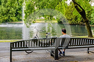 Young man day dreaming on a wooden bench in the park