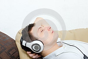 Young man daydreaming listening to music over headset