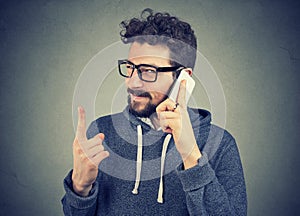 Young man with deceiving face expression talking on a phone tells lies photo