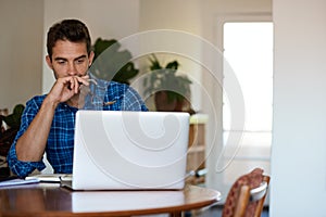 Young man deep in thought while working remotely from home photo