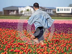Young Man with Denim Jacket Running in Tulip Field