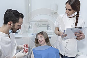 Young man dentist showing dental jaw model to female patient in dentist`s office