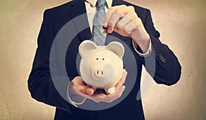 Young man depositing money in piggy bank