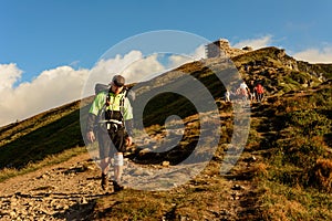 A young man descends from the top of the mountain Pip Ivan, observes the epic landscapes around the mountain, carries a large