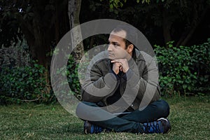 Young man different moods of expression cross leg sitting in a park from flat angle