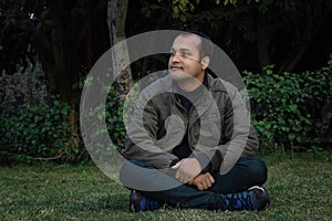 Young man different moods of expression cross leg sitting in a park from flat angle