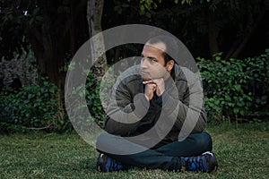 Young man different moods of expression cross leg sitting in a park from flat angle