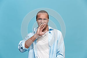 Young man with disgusted expression repulsing something, isolated on the blue
