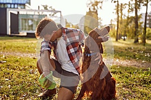 The young man is disgusted by the poop of his dog which he collects in the park. Friendship, walk, pets