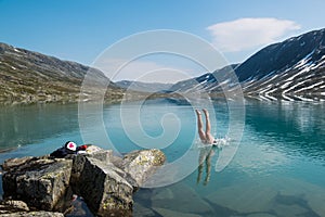 Young man dives into a cold mountain lake, Norway