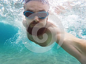 Young man diving in a blue clean water