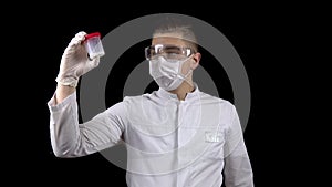 A young man doctor is checking sperm tests. A man examines a test jar containing semen on a black background.