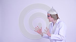 Young man doctor with tinfoil hat snapping fingers and looking shocked