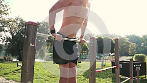 Young man does various bodyweight exercises at the horizontal bar