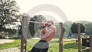 Young man does various bodyweight exercises at the horizontal bar