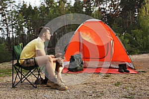 Young man with dog near camping tent