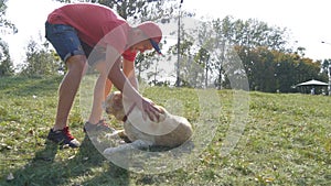 Young man and dog playing outdoor at nature. Labrador or golden retriever and his male owner spend time together at the