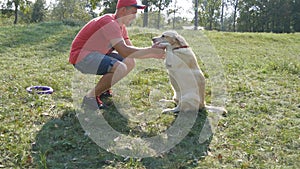 Young man and dog playing outdoor at nature. Labrador or golden retriever and his male owner spend time together at the