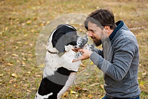 Young man with dog walks in autumn park.