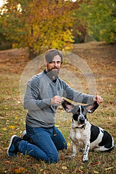 Young man with dog walks in autumn park.
