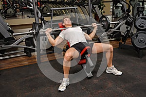 Young man doing Barbell Incline Bench Press workout in gym