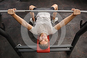 Young man doing bench press workout in gym